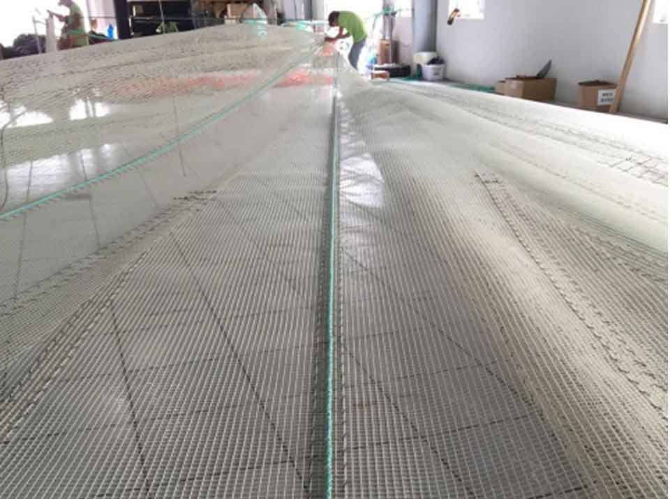 Workshop team spreading a large KGrid net panel
